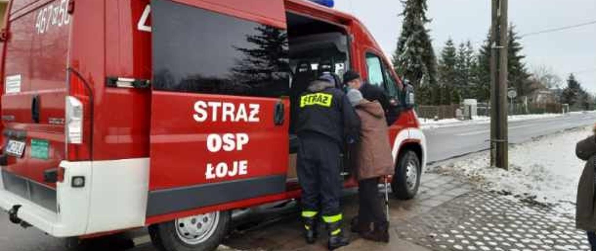 strażacy OSP pomagają seniorowi w transporcie na szczepienie. wejście do samochodu strażackiego