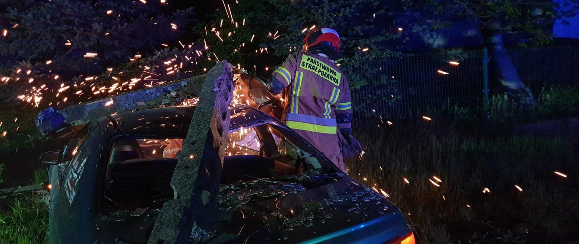 Wypadek samochodu osobowego w miejscowości Szydłowice - na zdjęciu widać strażaka wykonującego dostęp do samochodu