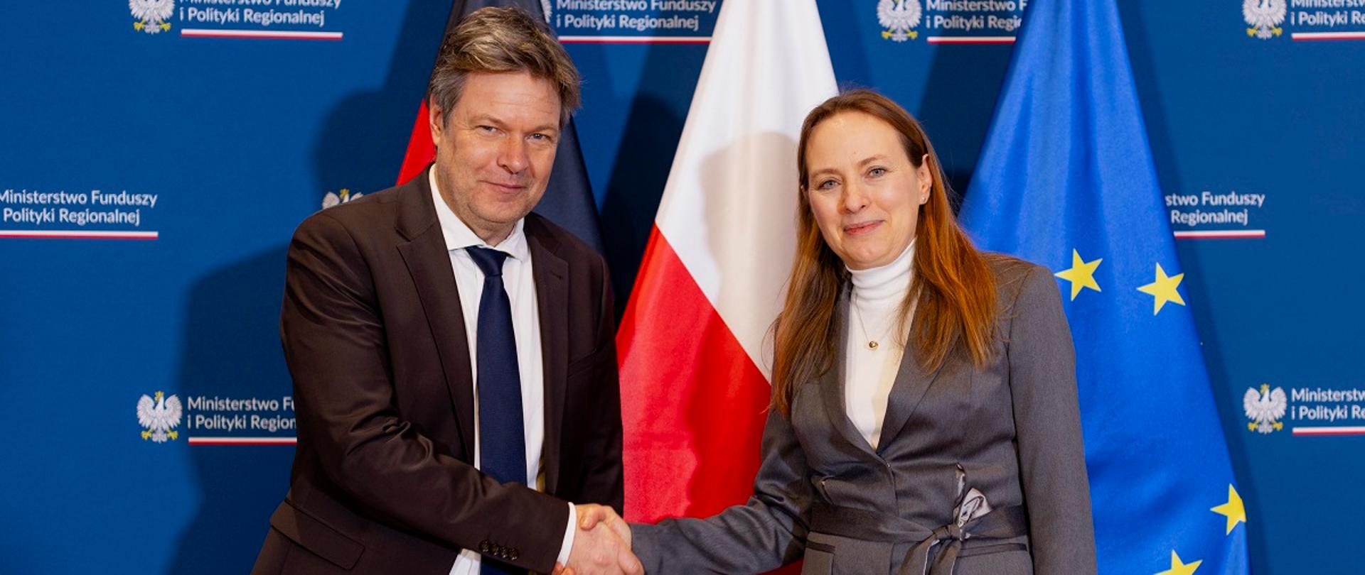 Minister funduszy i polityki regionalnej Katarzyna Pełczyńska-Nałęcz z wicekanclerzem Niemiec Robertem Habeckiem, minister ściska dłoń z kanclerzem, za ich placami flagi Polski, Niemiec i UE