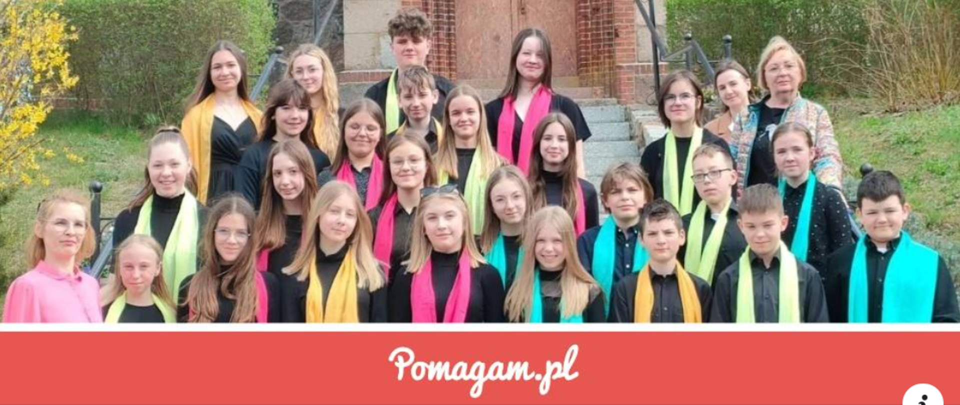 Chór szkolny na schodach kościoła w kolorowych szalikach. 