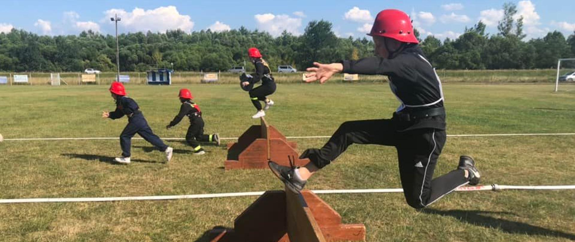 Strażacy przeskakują płotek