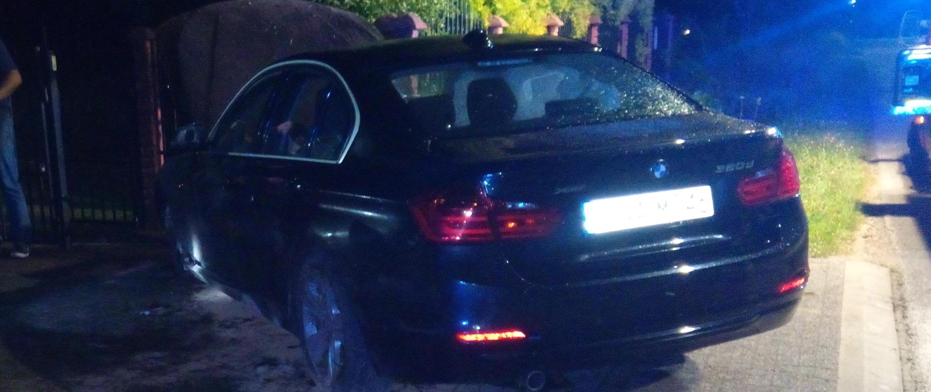 Zdjęcie przedstawia tył samochodu osobowego, który zderzył się z przepustem drogowym i stoi na prywatnej posesji. 