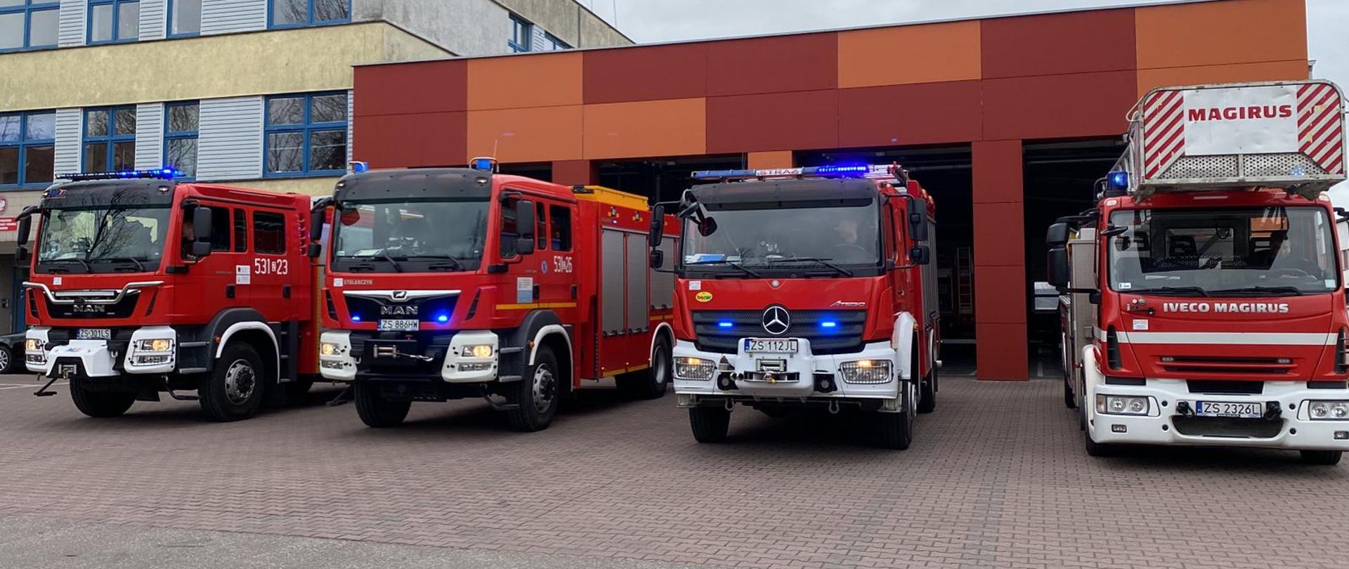 Samochody JRG Stargard z włączonymi sygnałami świetlnymi przed bramami.