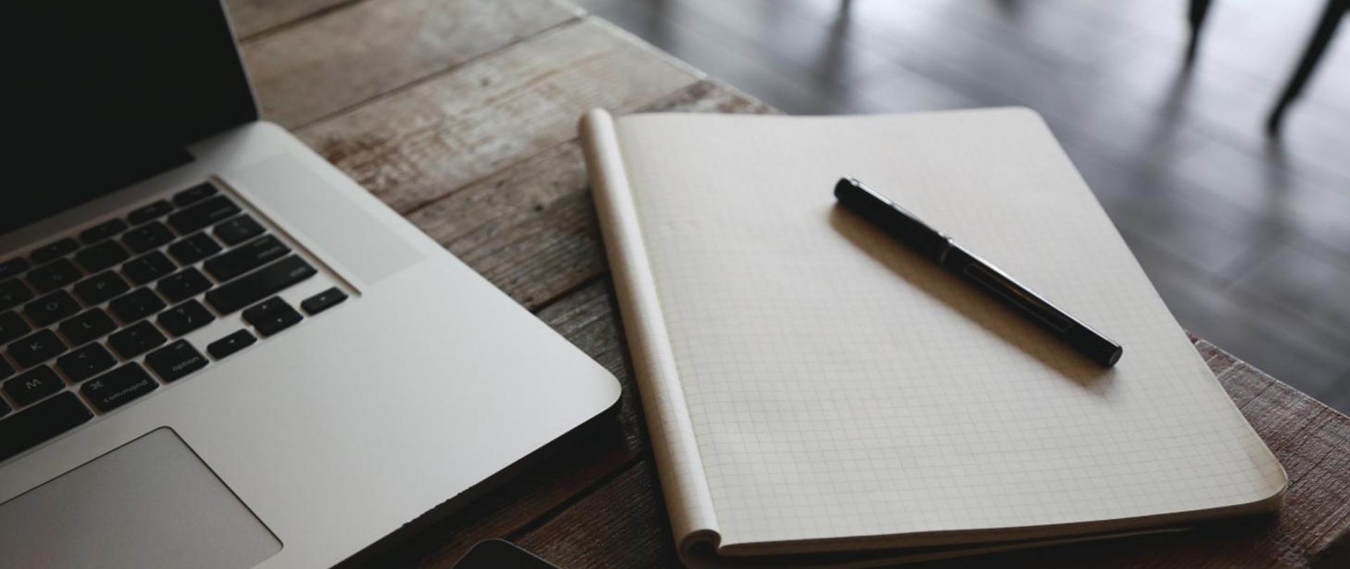 Laptop z notatnikiem i długopisem