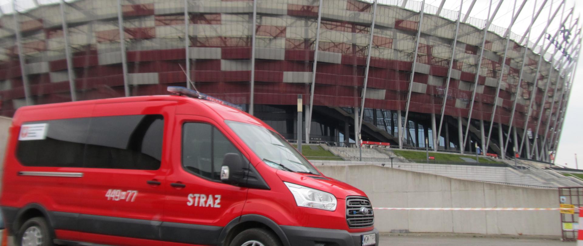 Na parkingu przy Stadionie Narodowym stoi samochód strażacki typu mikrobus.