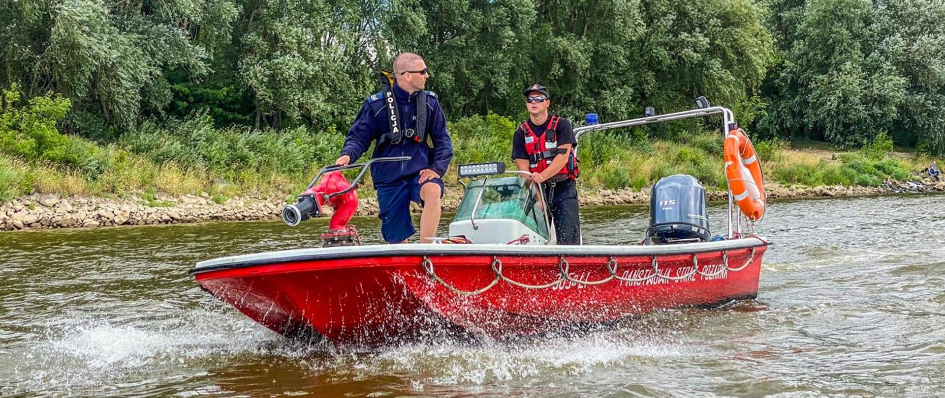 Funkcjonariusz PSP wraz z funkcjonariuszem na czerwonej łodzi patrolują akwen wodny