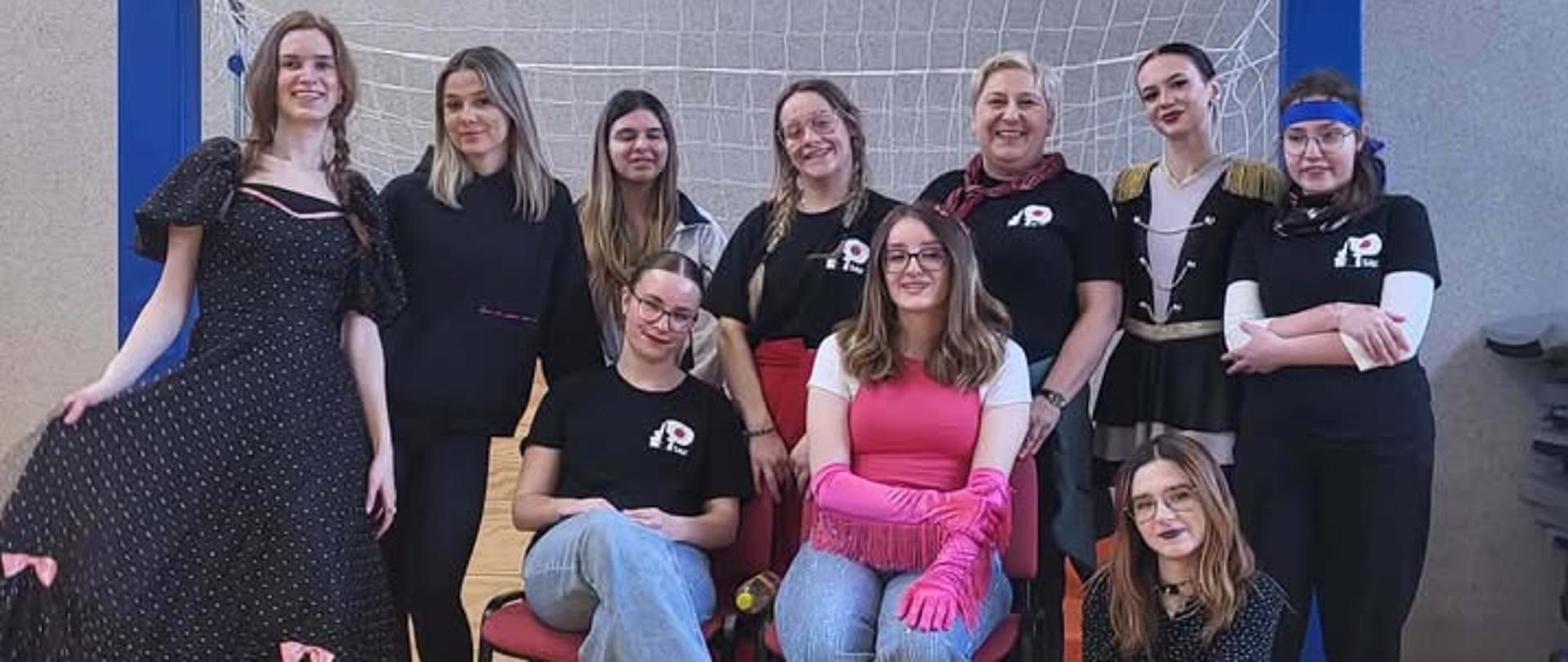 Zdjęcie przedstawia grupę słuchaczek oraz nauczycielką Studium, które pozują, stoją obok siebie na tle bramki piłkarskiej. 