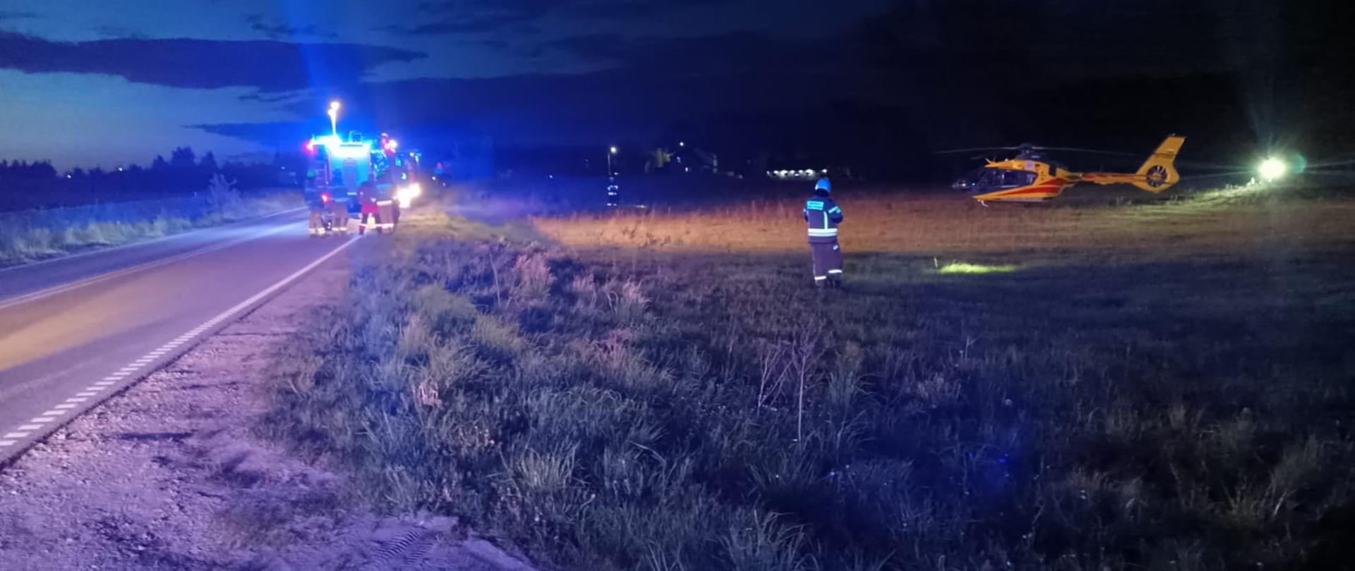 W tle widać strażaków, wozy strażackie oraz śmigłowiec lotniczego pogotowia ratunkowego