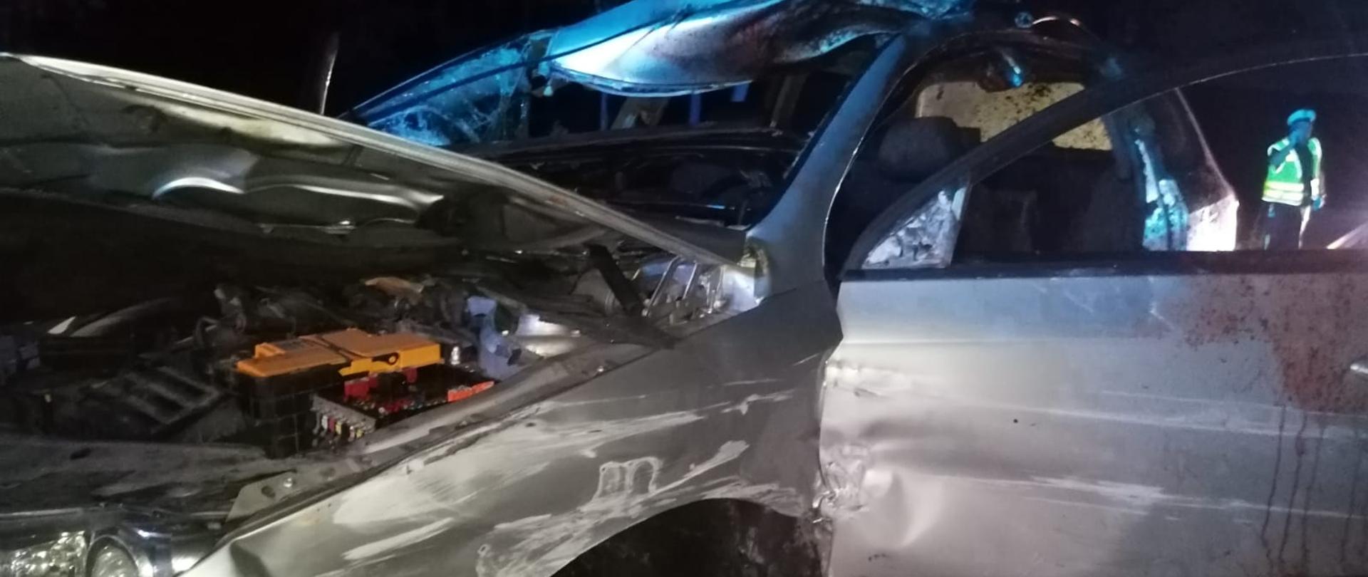 Uszkodzone srebrne auto, otwarte drzwi i maska.