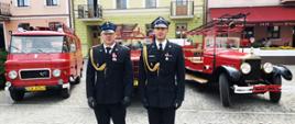 Zdjęcie awansowanych funkcjonariuszy z Komendy Powiatowej PSP w Makowie Mazowieckim na tle zabytkowych samochodów strażackich.