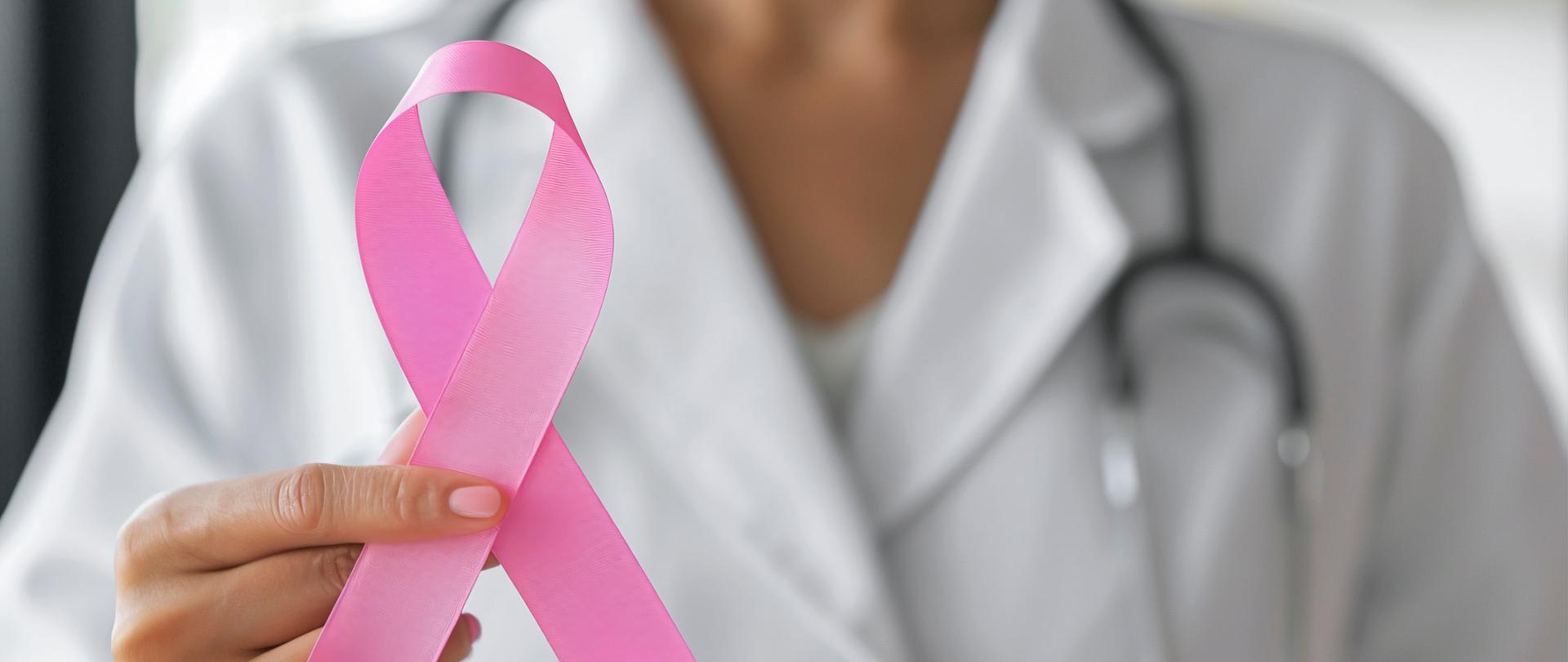 kobieta w kitlu lekarskim trzymająca różową wstążeczkę symbol profilaktyki raka piersi