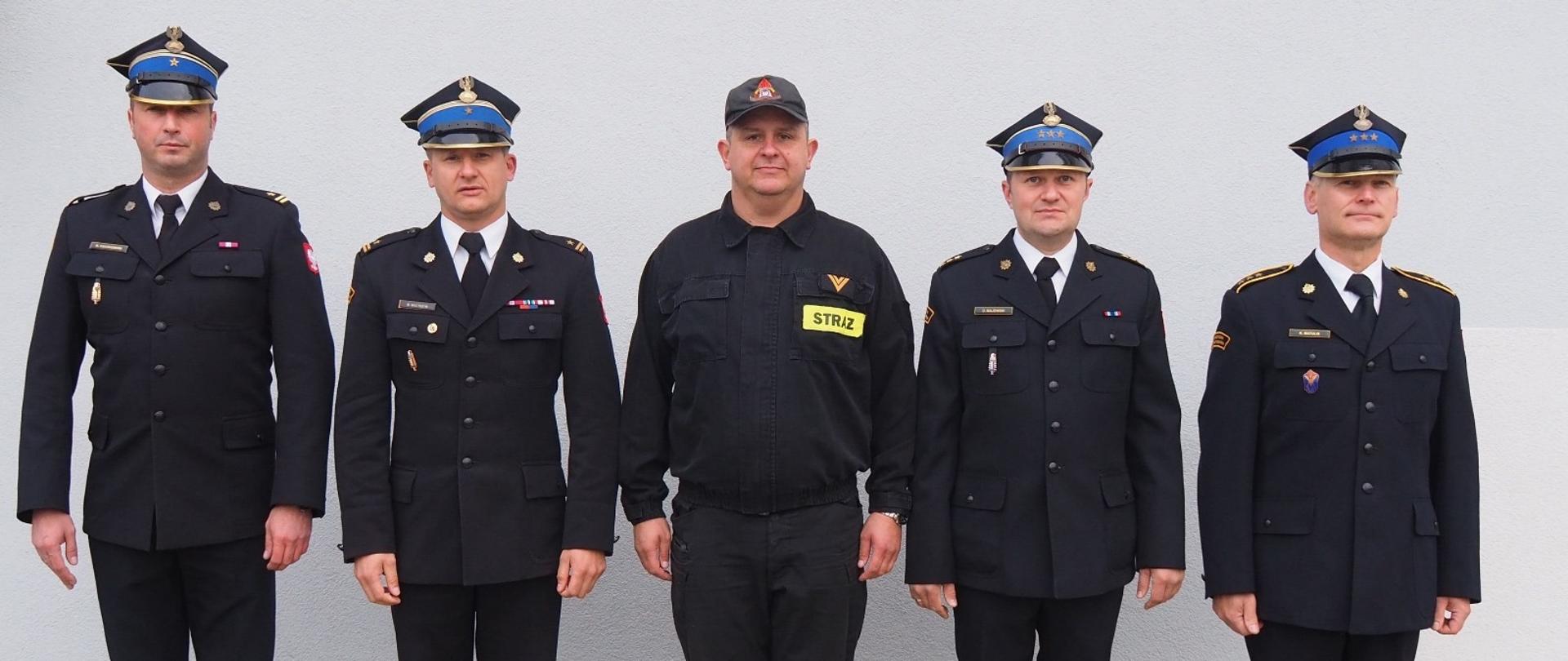 Na placu Jednostki Ratowniczo-Gaśniczej nr 2 w Trzciance stoją w szeregu funkcjonariusze Państwowej Straży Pożarnej – od lewej: zastępca komendanta PSP w Czarnkowie, komendant PSP w Czarnkowie, strażak odchodzący na emeryturę, dowódca JRG 2 w Trzciance oraz jego zastępca.