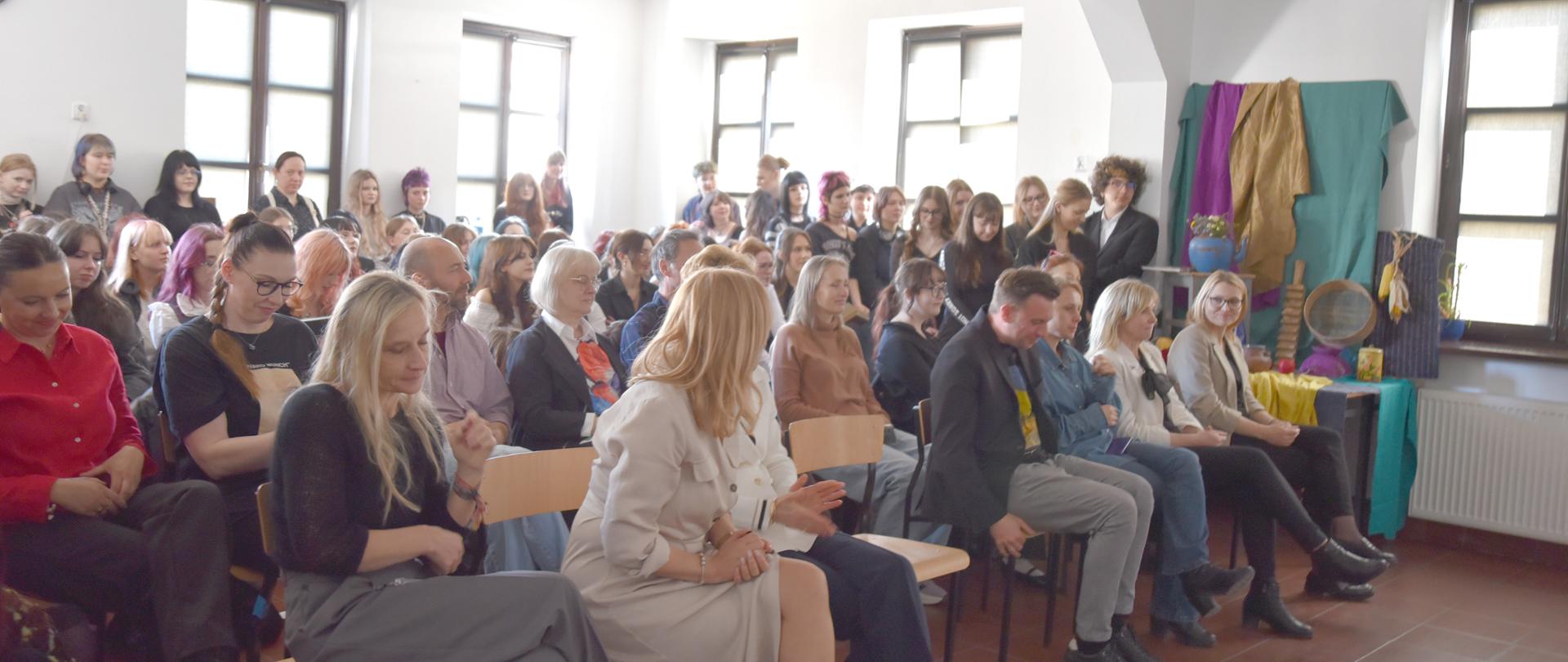 zdjęcie grupowe , na auli uczniowie wraz z nauczycielami siedzą w ławkach