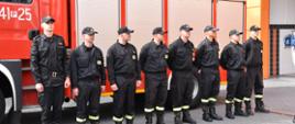 Strażacy stoją w szeregu przed samochodem
