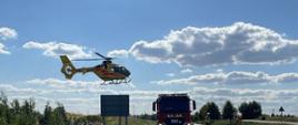 Śmigłowiec LPR podczas odlotu. W tle samochód pożarniczy oraz strażacy
