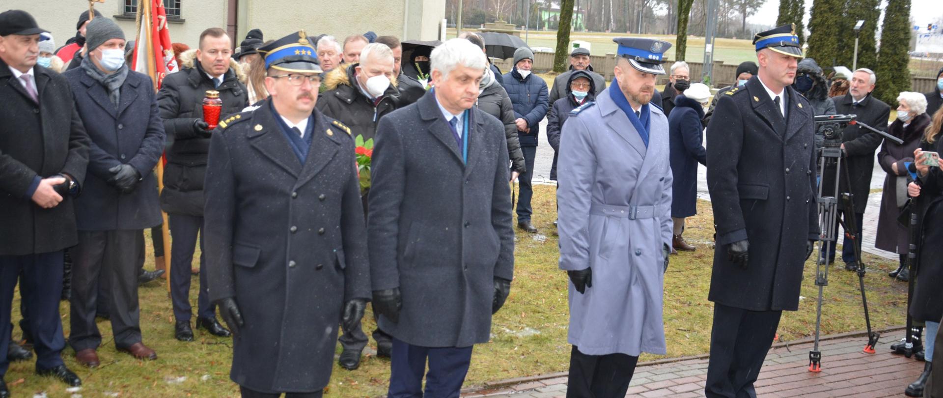 Zdjęcie przedstawia uczestników uroczystości podczas złożenia kwiatów przy grobie ks. Stanisława Suchowolca. 