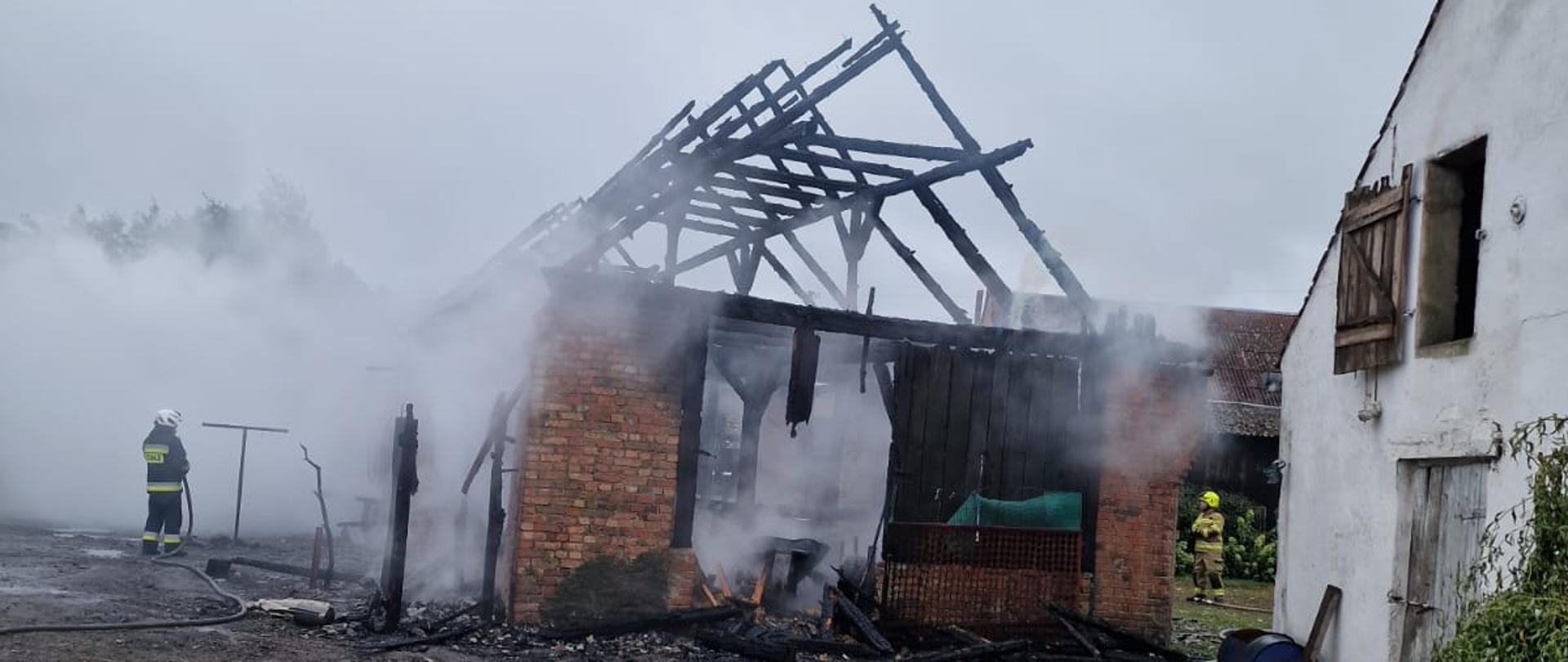 Zdjęcie przedstawia ugaszony budynek gospodarczy, wokół którego unosi się para wodna.