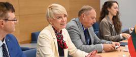 Przy stole konferencyjnym siedzą dwie kobiety i dwóch mężczyzn i słuchają wypowiedzi osoby siedzącej naprzeciwko