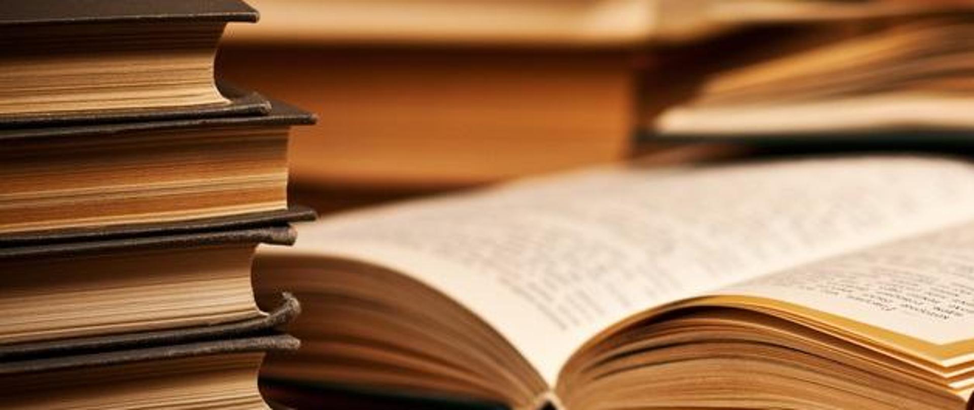 stół , a na nim dużo książek poukładanych jedna na drugiej