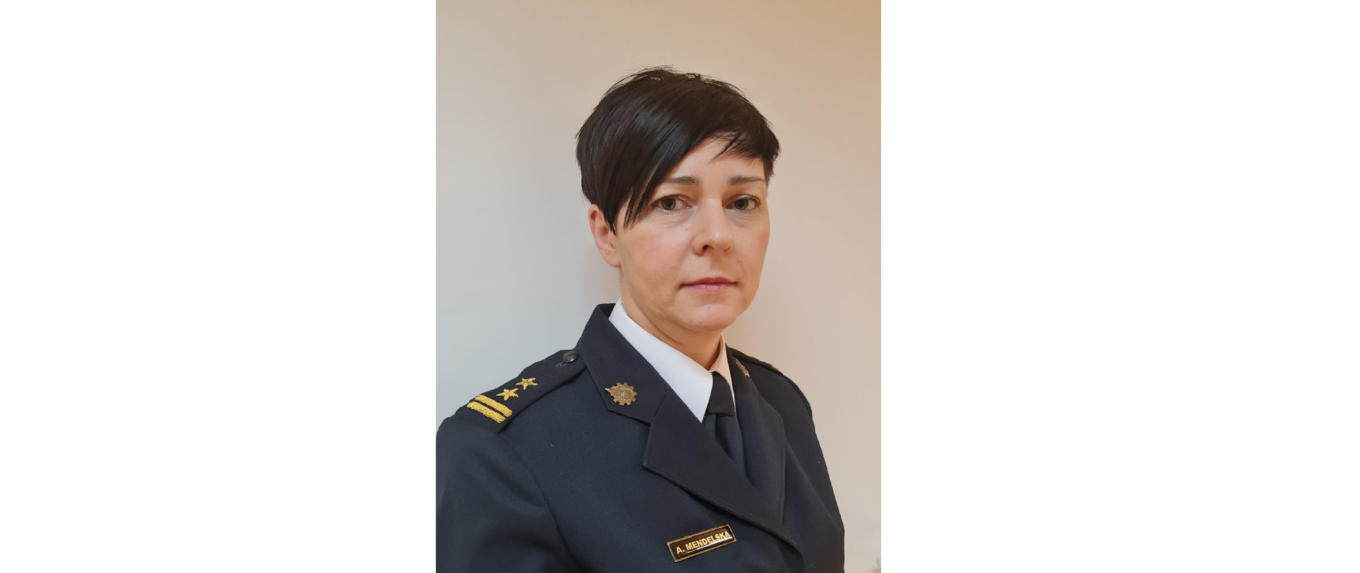 Zastępca Komendanta, Kobieta, krótkie włosy w mundurze galowym na białym tle. Widoczny stopień brygadiera oraz odznaczenie. 