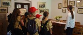 Widok z tyłu. Członkowie MDP oglądają eksponaty zgormadzone w Izbie Pamięci w pałacu w Ryczowie. Po prawej stronie wolontariuszka ze szkoły podstawowej.
