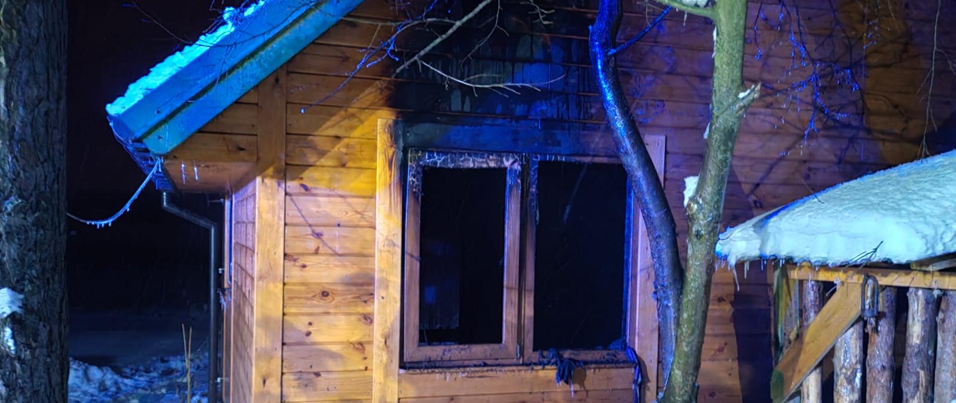 Na zdjęciu widoczny drewniany domek i nadpalone okno przez które wychodziły wcześniej płomienie. 