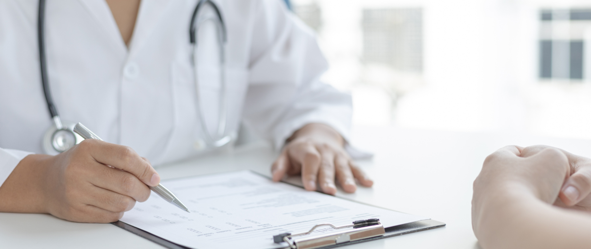 Lekarz siedzący przy biurku i wypełniający ankietę