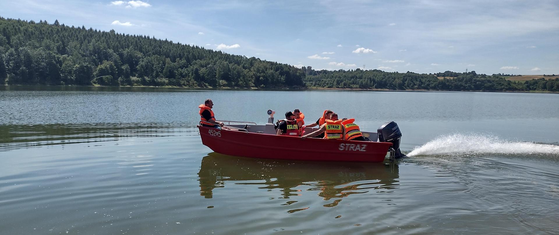 Strażacy w łodzi ratunkowej patrolujący zalew wodny 