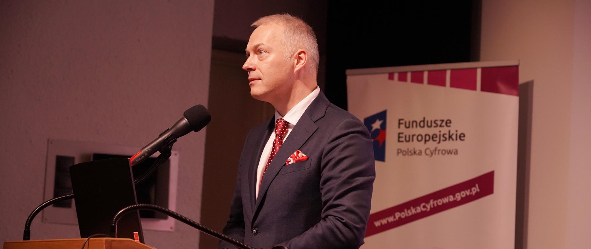  Wiceminister Jacek Żalek stoi przy pulpicie i mówi do zgromadzonych gości.