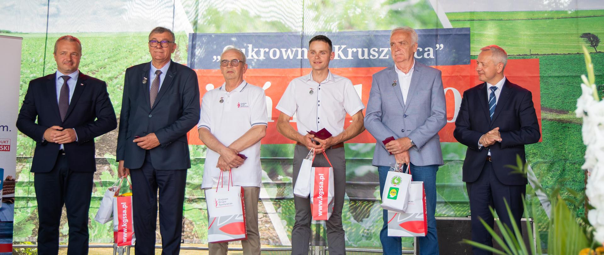 Osoby nagrodzone stoją na scenie.