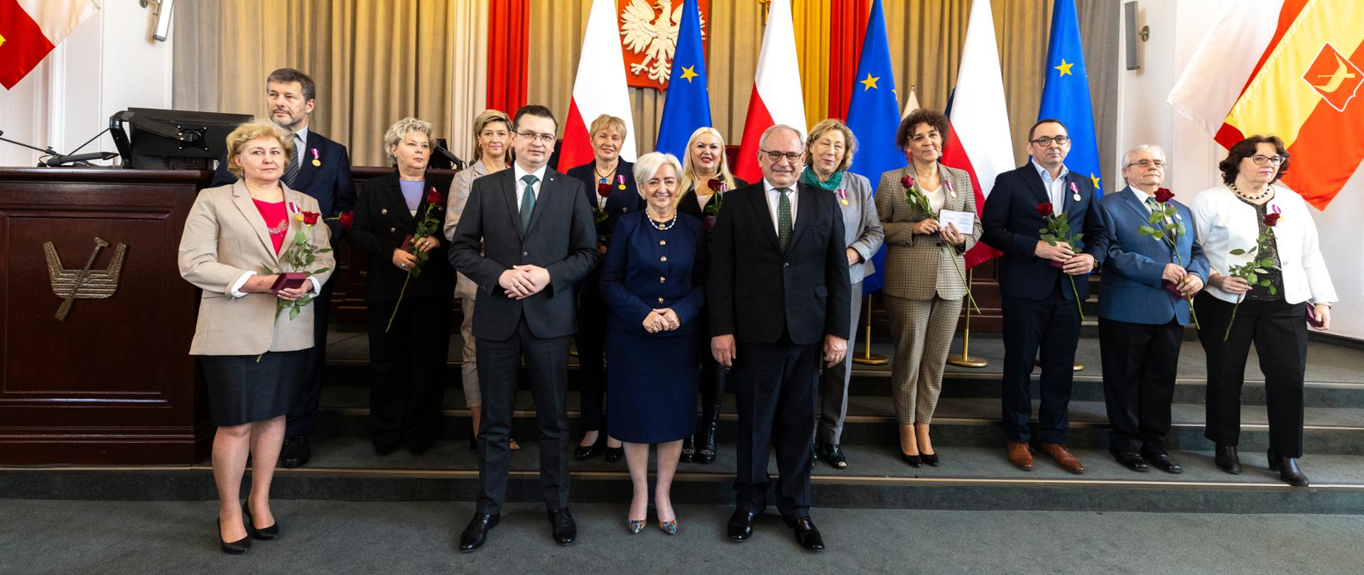 Pamiątkowa fotografia wojewody łódzkiego Doroty Ryl, wicewojewodów: Marka Mazura i Grzegorza Majewskiego z pracownikami wyróżnionymi Złotymi Medalami za Długoletnią Służbę. 