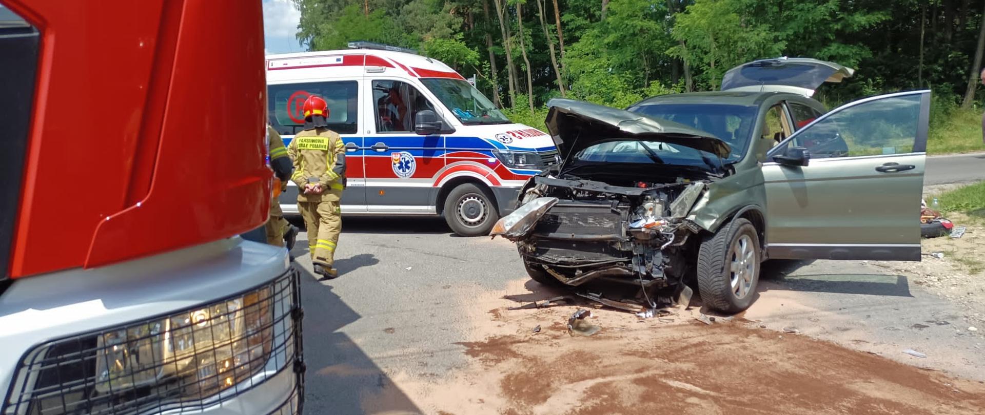 Na zdjęciu widać przód drugiego samochodu osobowego biorącego udział w wypadku- uszkodzony cały przód pojazdu, na drodze wycieki płynów eksploatacyjnych z pojazdu, auto na środku skrzyżowania, po lewej przód samochodu ratowniczo-gaśniczego JRG Dabrowa Tarnowska.