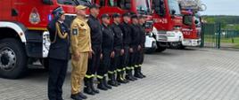 Strażacy stoją w pozycji zasadniczej oddając hołd poległemu żołnierzowi. 