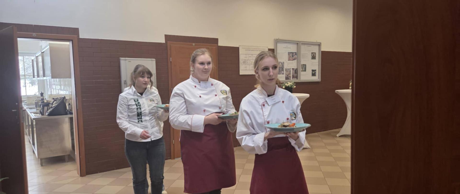 Zdjęcie przedstawia uczennice ZSCKR w Janowie serwujące dania.