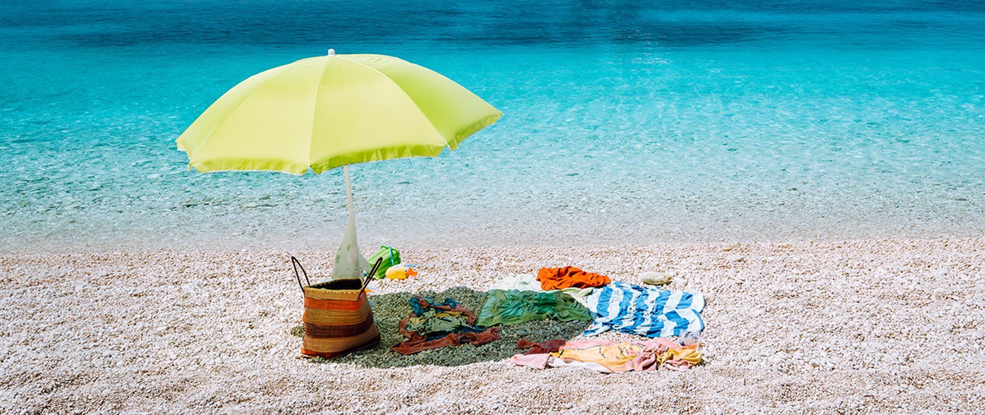 Plaża, nad wodą rozbity parasol.