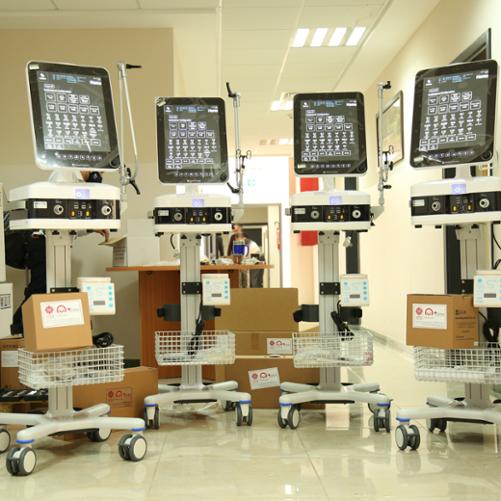 Cztery urządzenia medyczne z ekranami na kółkach i z naklejkami Caritas i Polska pomoc