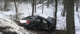 Zdjęcie przedstawia uszkodzony samochód osobowy marki CHEVROLET CRUZE znajdujący się na skraju przydrożnego lasu.