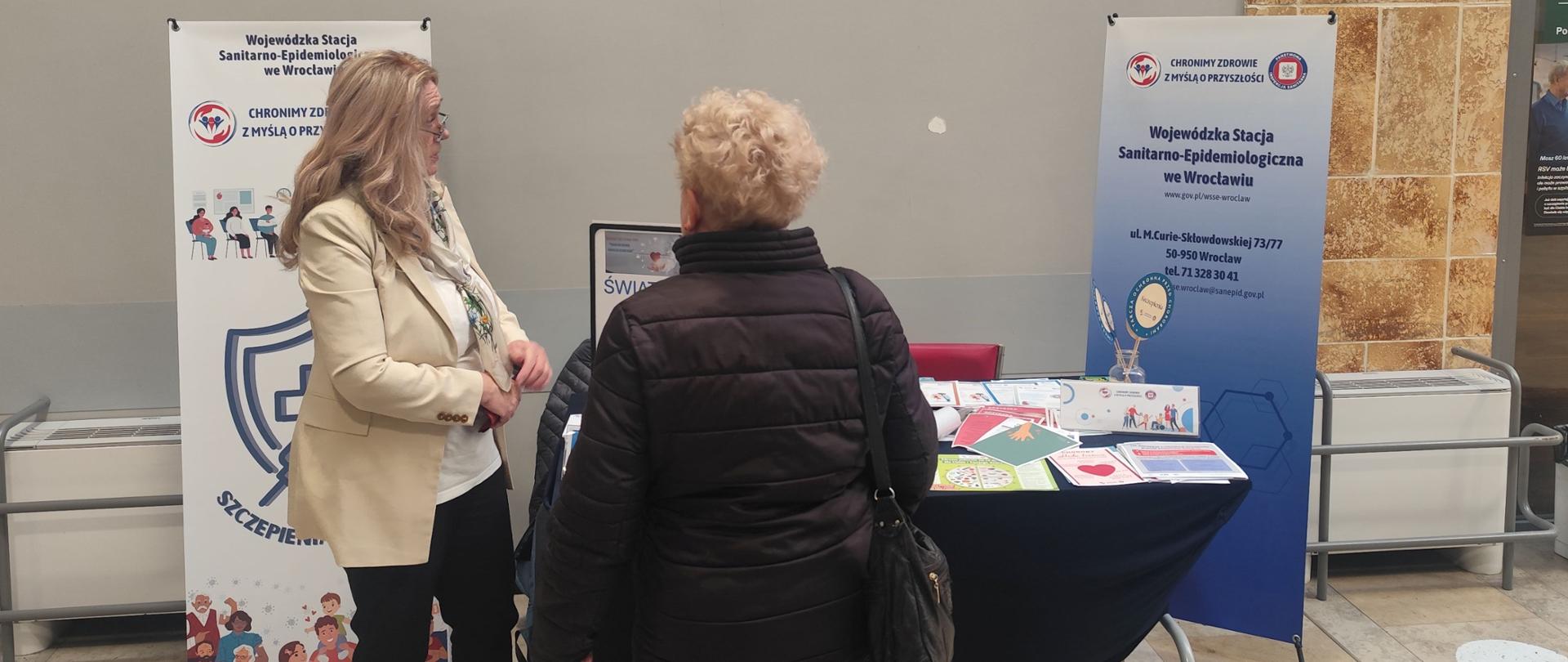 Osoby stojące przy stoisku edukacyjnym