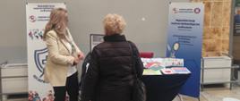 Osoby stojące przy stoisku edukacyjnym