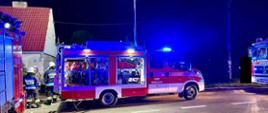 Samochód strażacki przed budynkiem, jest noc