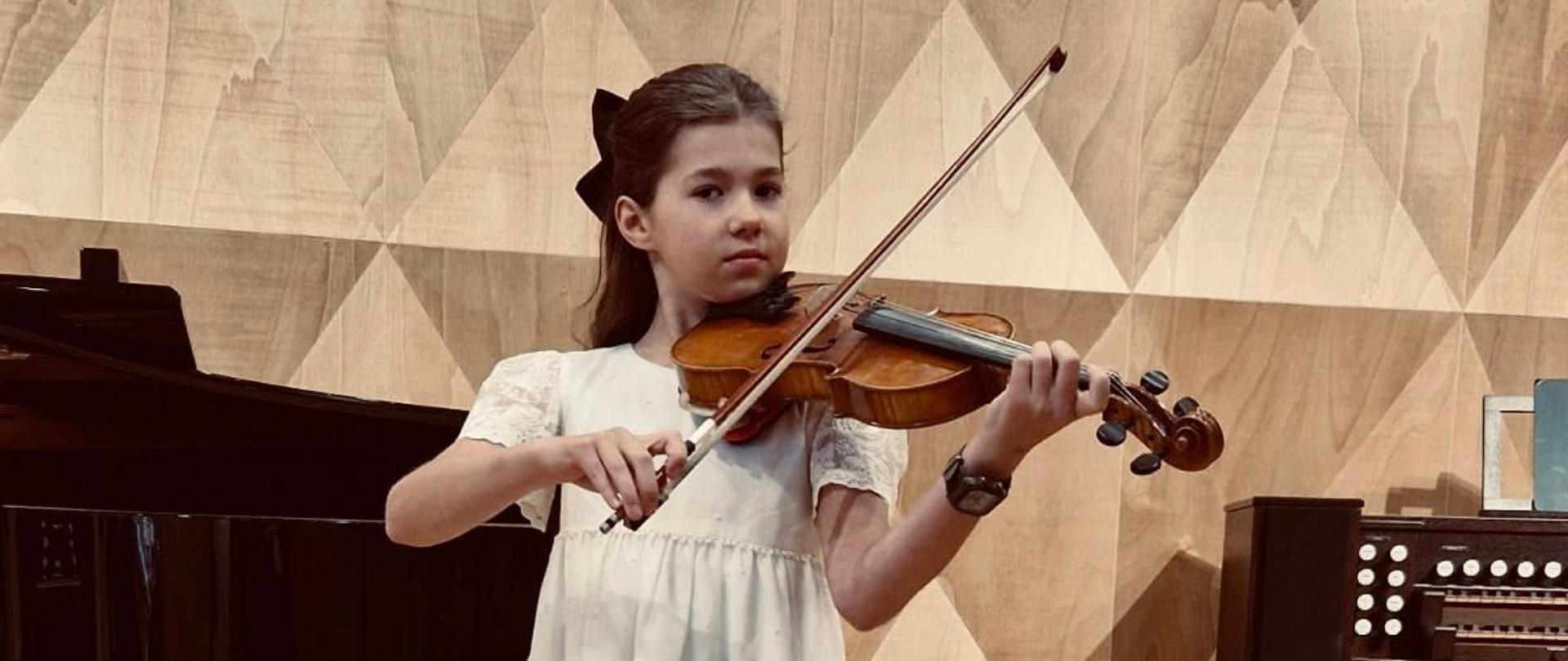 Dziewczynka na scenie sali koncertowej gra na skrzypcach