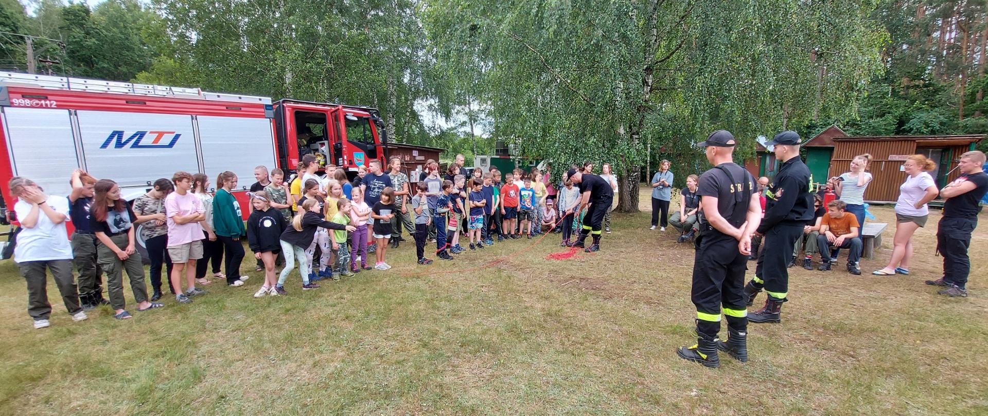 Strażacy pokazują młodzieży jak posługiwać się rzutką ratowniczą.