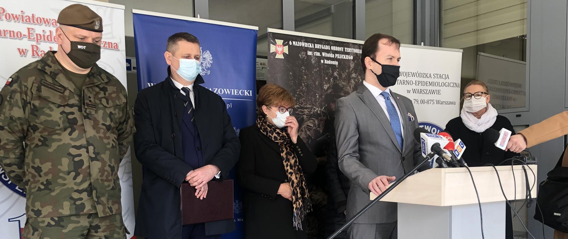 Brefing prasowy. Stoi grupa prelegentów przed siedzibą PSSE w Radomiu.