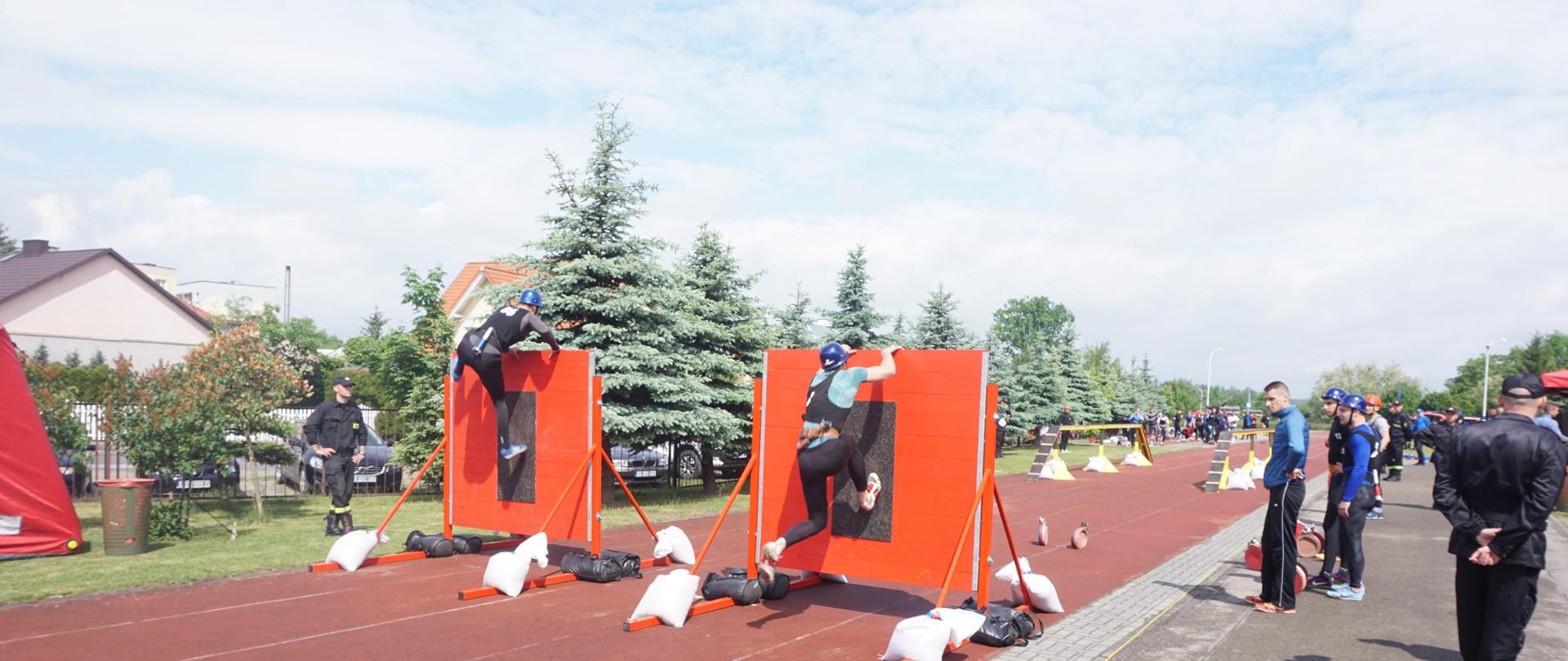 Zawodnicy pokonujący przeszkody w konkurencji pożarniczy tor przeszkód