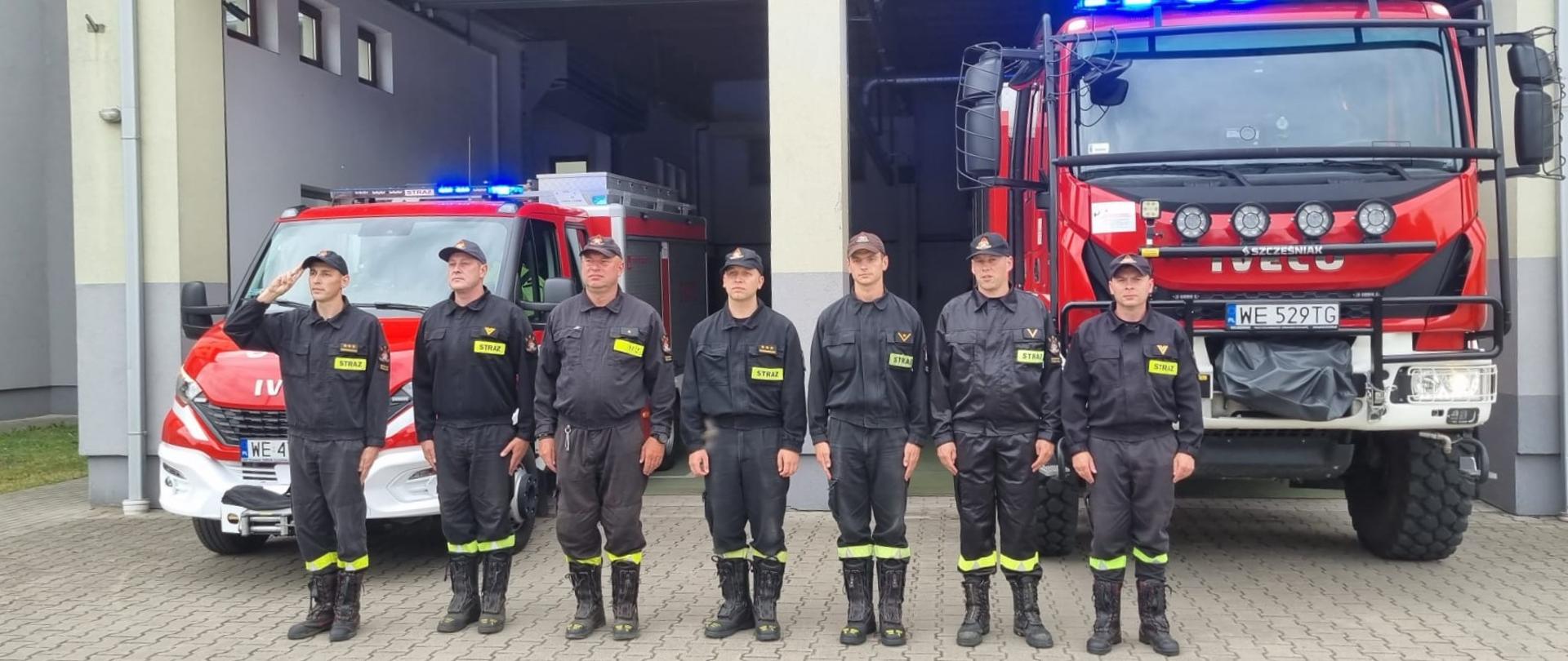 79. rocznica wybuchu Powstania Warszawskiego - Strażacy JRG Sokołów Podlaski stojący na zbiórce w umundurowaniu, na tle samochodów pożarniczych.