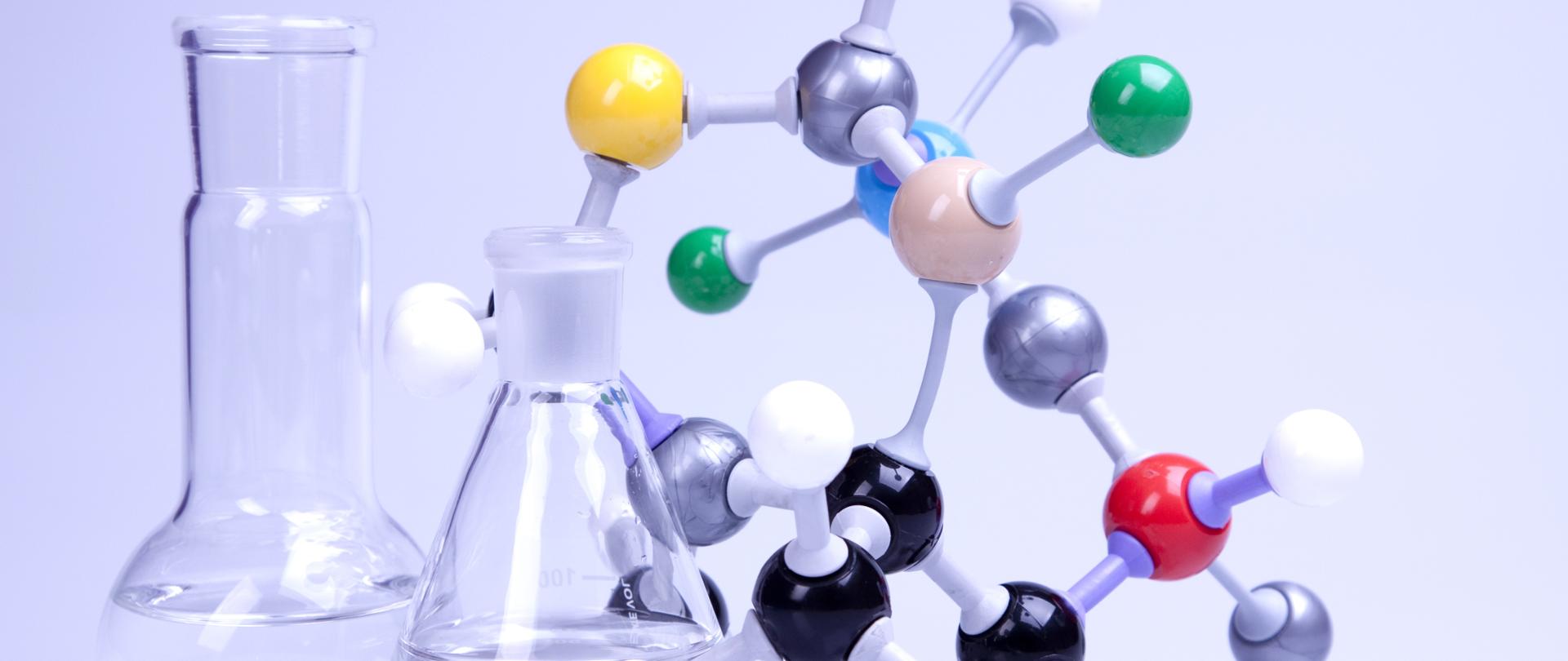 Zdjęcie przedstawia fiolki i model naukowy.