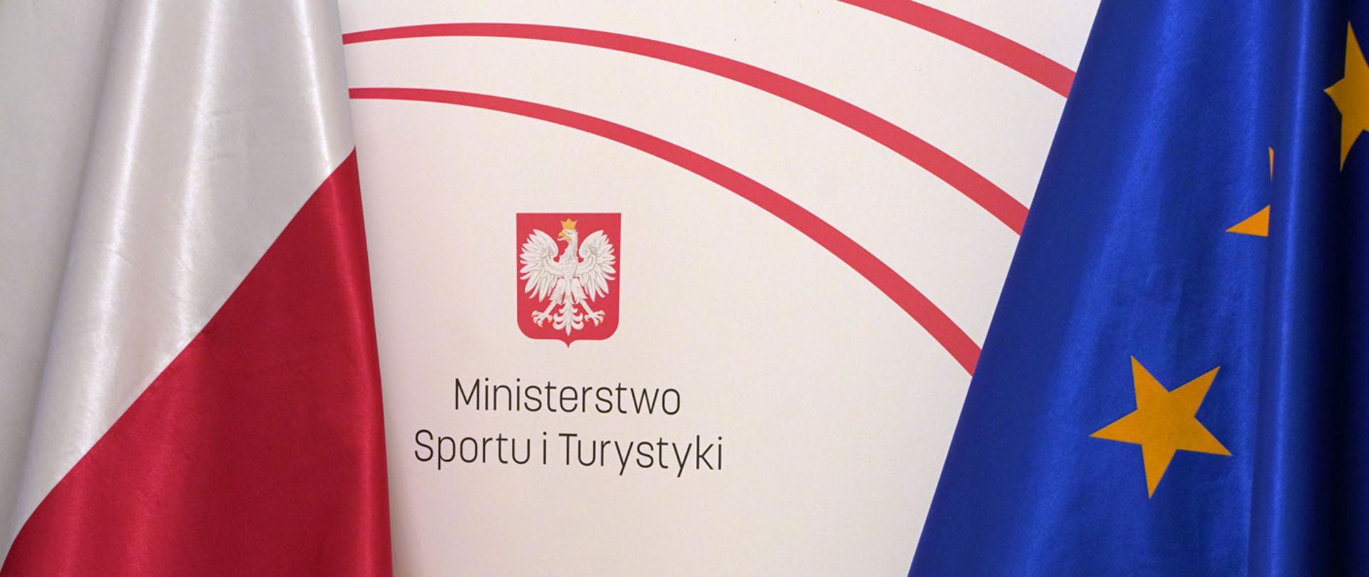 Flagi Polski i Unii Europejskiej, na środku logo i napis Ministerstwo Sportu i Turystyki