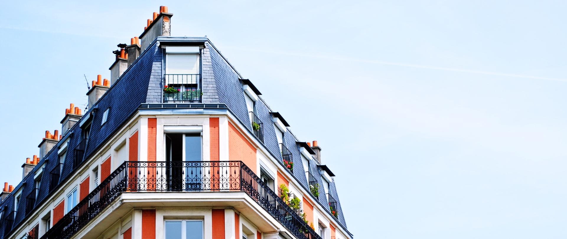 na zdjęciu wysoka kamienica z wieloma balkonami i oknami - na tle nieba