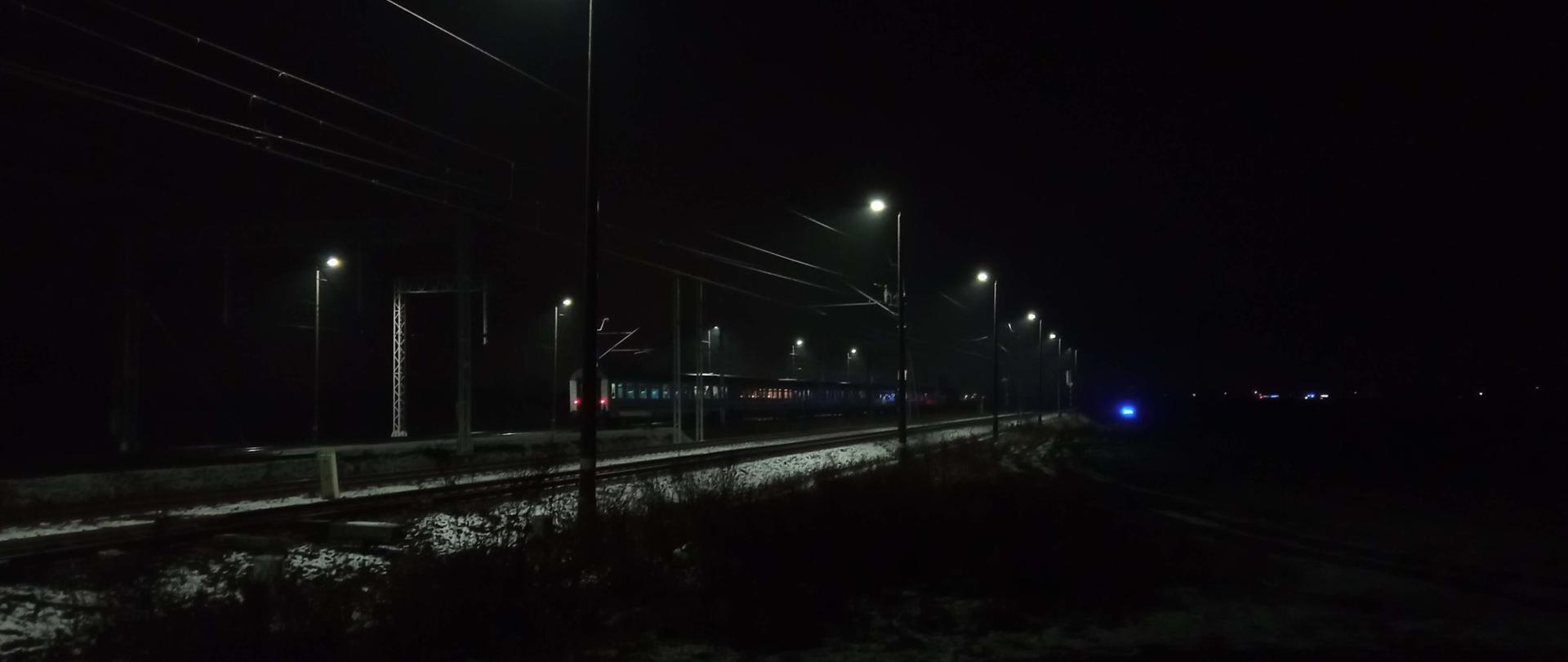 Zdjęcie przedstawia tory kolejowe i stojący pociąg