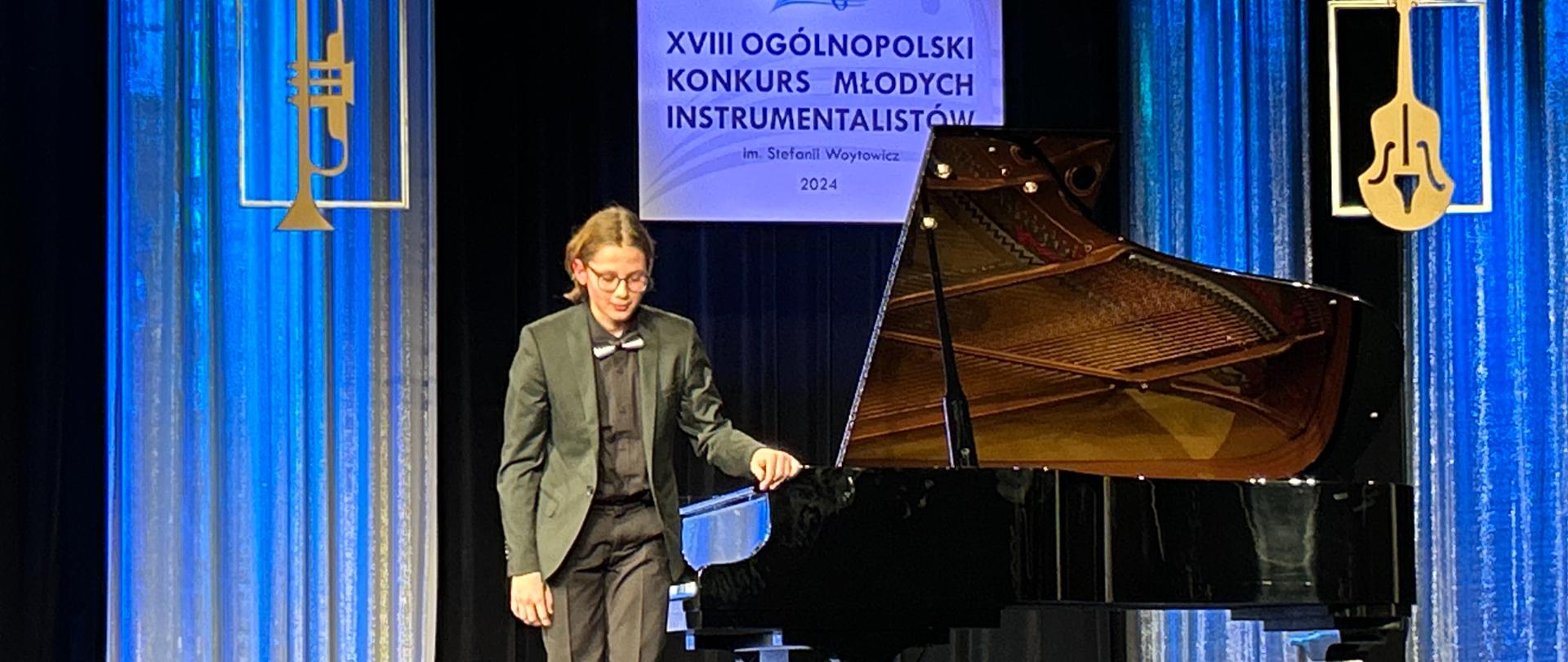 Zdjęcie przedstawia scenę jasielskiego domu kultury a na niej kłaniającego się do publiczności Gabriela Kuizinasa. Obok chłopca czarny fortepian. 